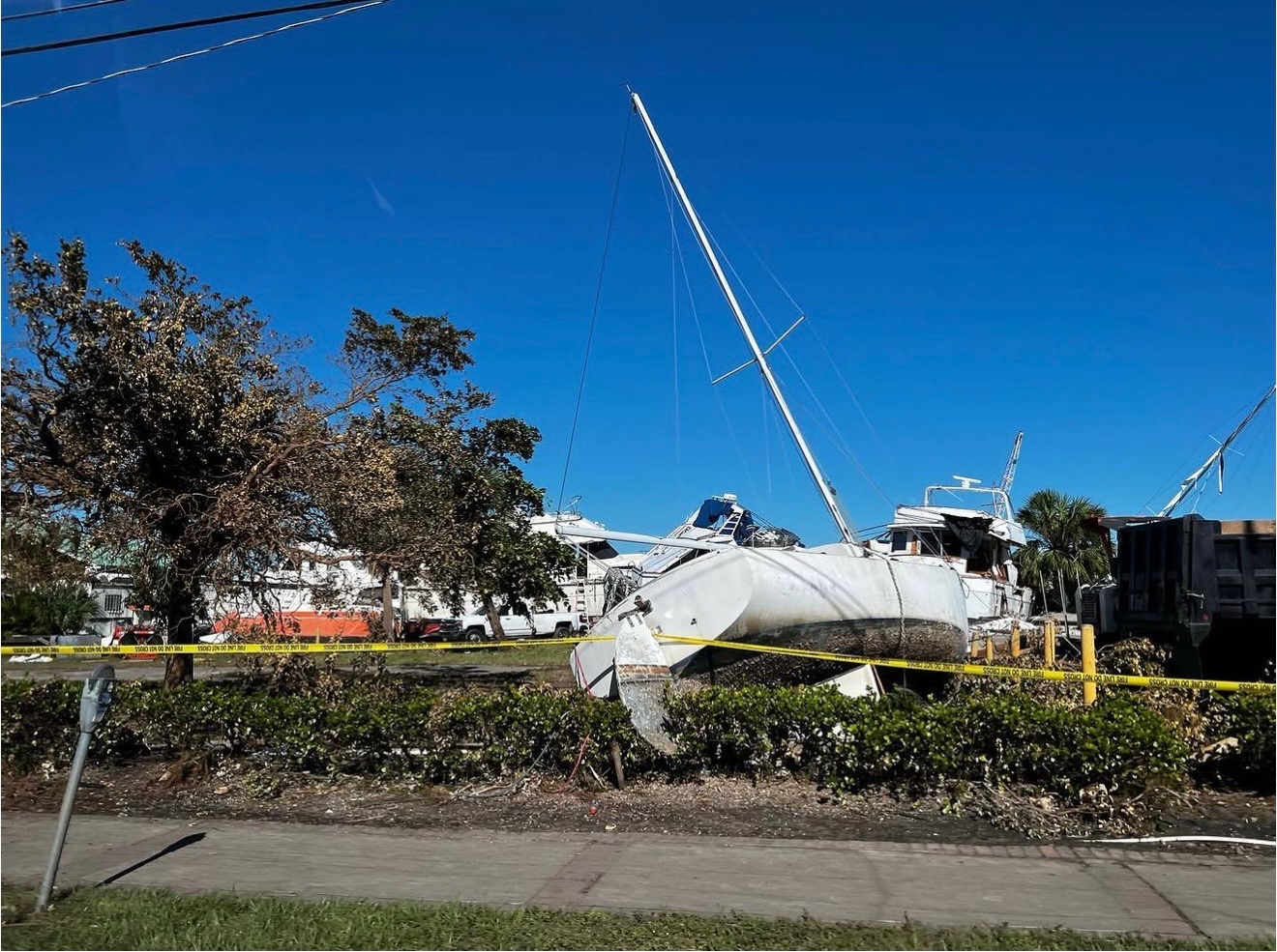 Sailboat displaced ashore with storm damage and caution tape marking the hazard zone
