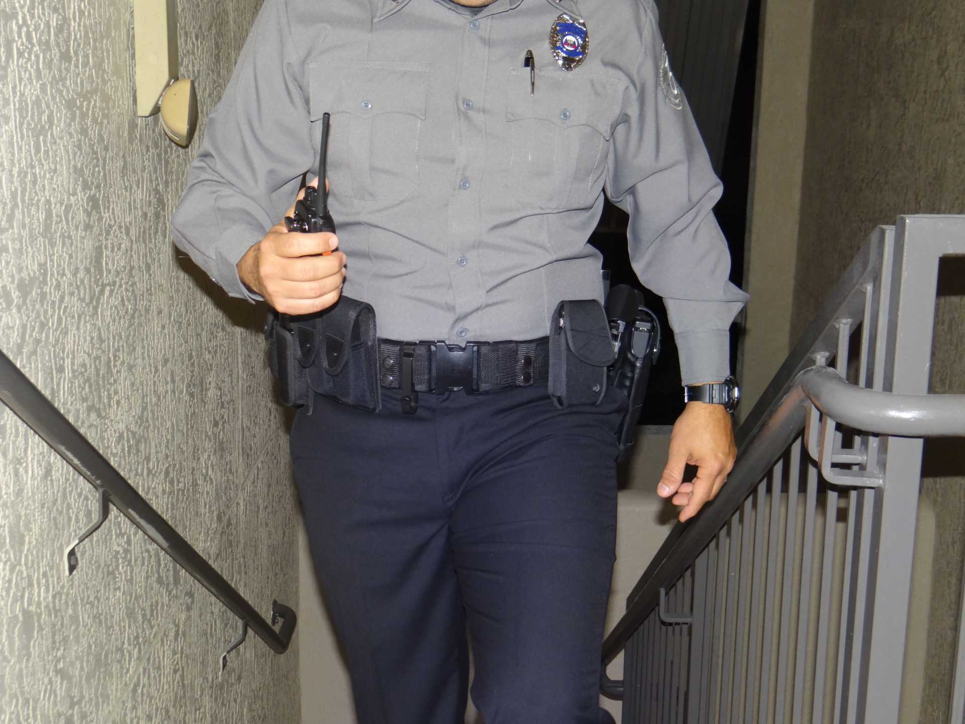 Uniformed 365 security officer with radio and duty belt patrolling stairwell