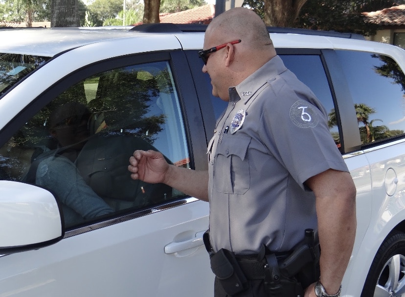 365 SMG officer in uniform verifying credentials at a vehicle access point